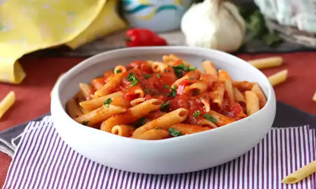 En skål med pasta arrabiata, toppad med färsk persilja. En klassisk italiensk rätt som värmer själen.