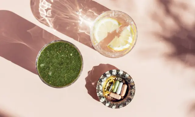 Grön smoothie, citronvatten och kapslar med spårämnen i en vacker ljusmiljö.