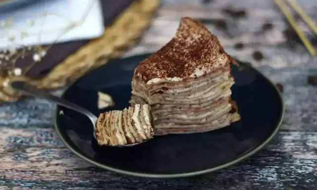 En skiva pannkakstårta med lager av grädde och kakao, perfekt för ett tiramisu recept.