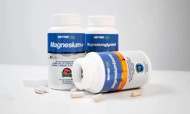 Tre burkar kosttillskott med magnesium. En burk ligger ner och visar texten "Magnesiumtaurat", som bidrar till att minska trötthet och utmattning, vilket är viktigt för magnesium i kroppen.
