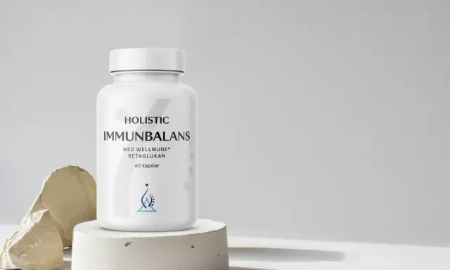 En vit burk med "Immunbalans" och "betaglukan" text. Minimalistisk design med stenar och betong.