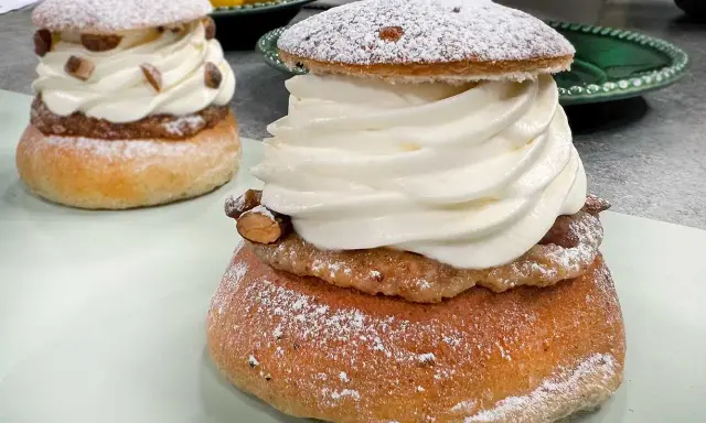 Två fluffiga semlor med rikligt med grädde och mandelmassa till semlor. Pudrade med florsocker och garnerade med mandelbitar.