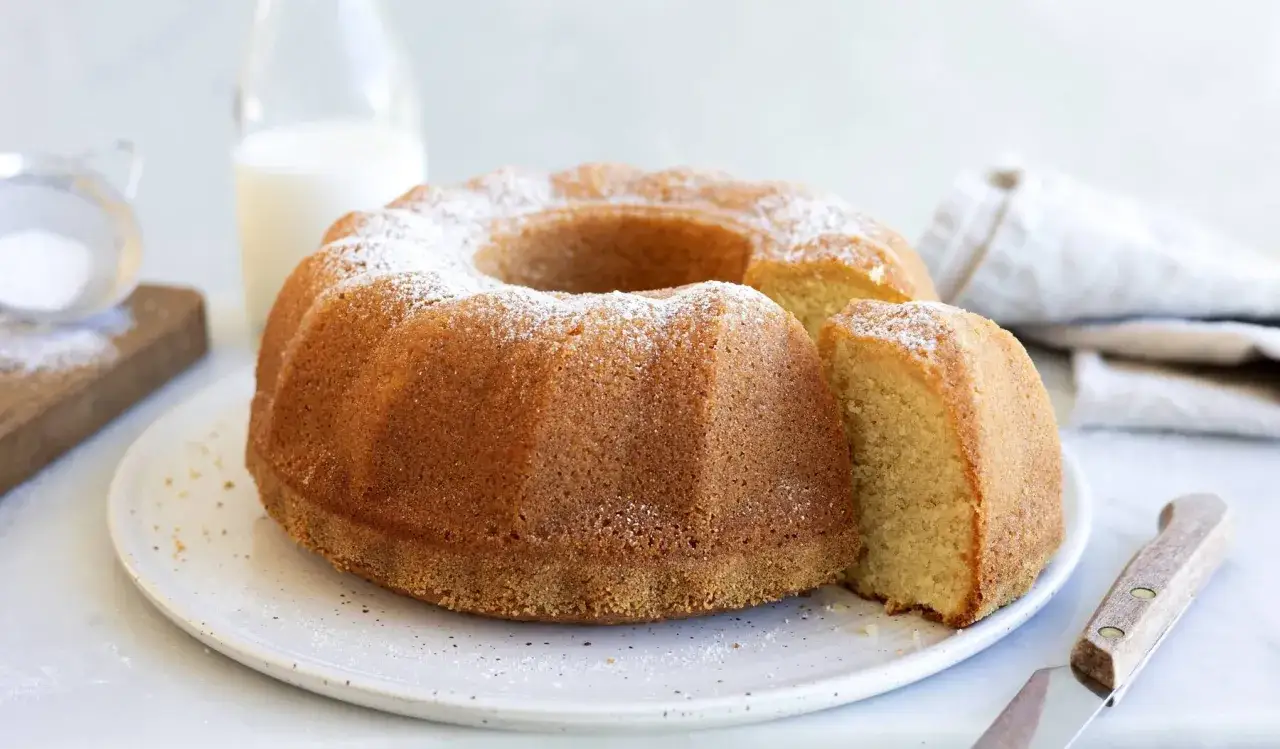 En gyllene sockerkaka med pudrat florsocker, perfekt f&ouml;r ett enkelt sockerkaka recept. En bit &auml;r uppskuren.
