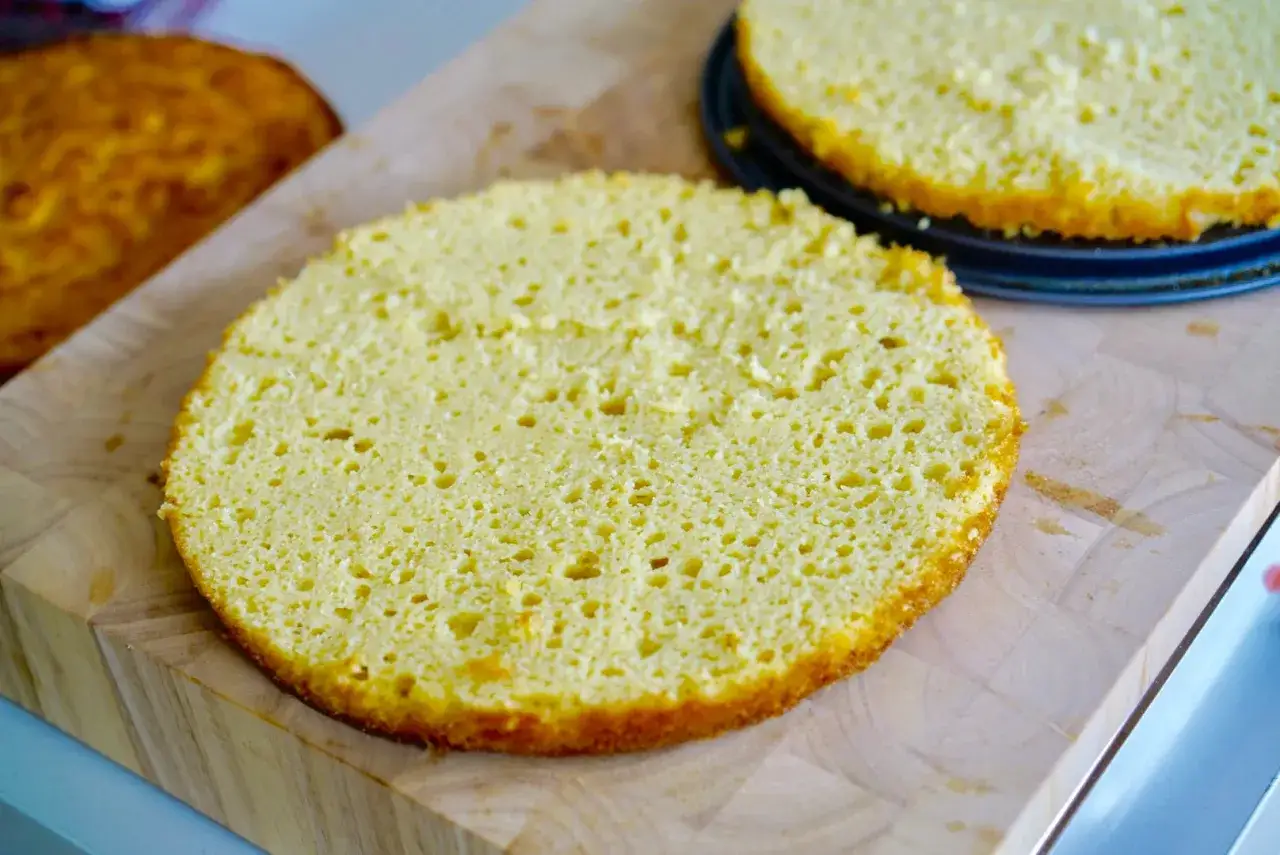 Tv&aring; runda, fluffiga glutenfri t&aring;rtbotten ligger p&aring; en sk&auml;rbr&auml;da. En ligger i en form, den andra bredvid.