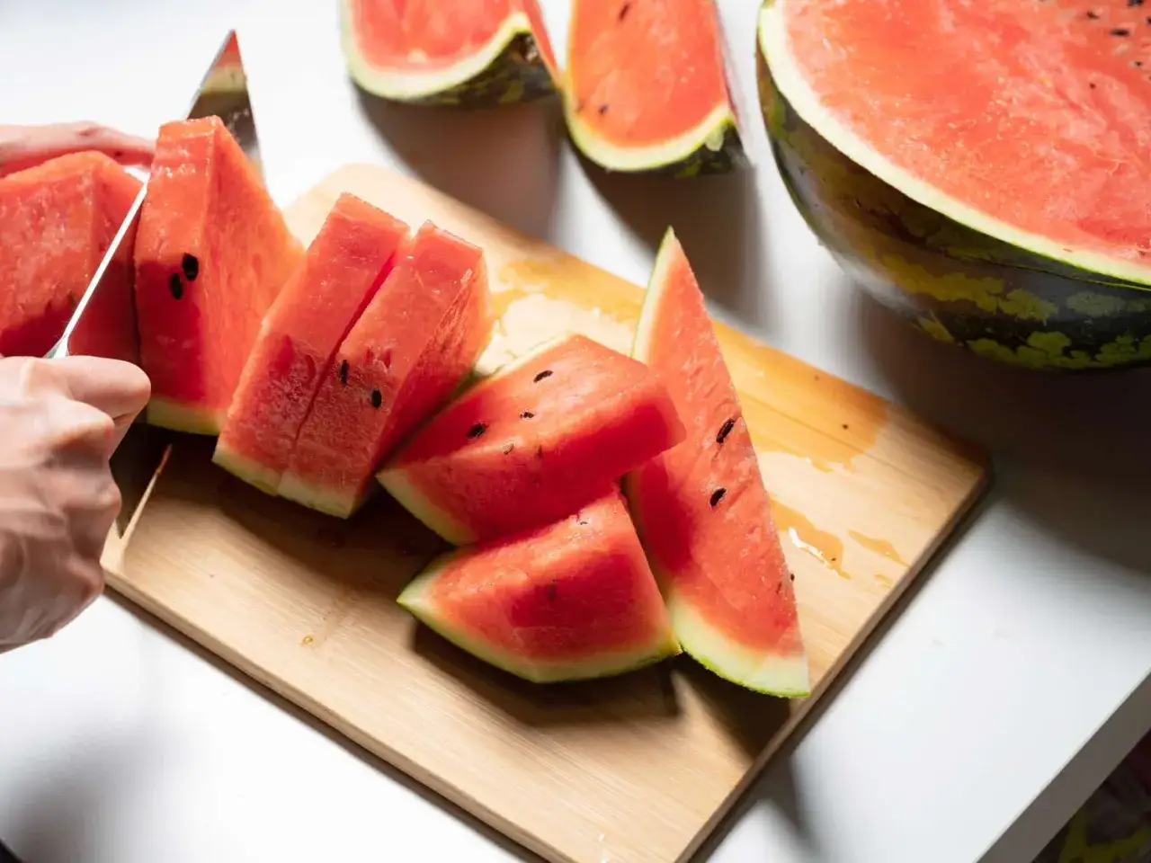 Skivor av saftig vattenmelon sk&auml;rs upp p&aring; en sk&auml;rbr&auml;da. Hoppas att inte f&aring; ont i magen av vattenmelon!