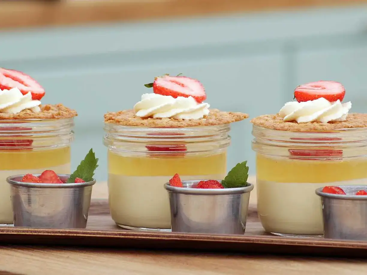 Tre dessertburkar med vaniljkr&auml;m, citrongel&eacute;, vispgr&auml;dde, jordgubbar och havreflarn. Ett perfekt havreflarn recept f&ouml;r sommaren!