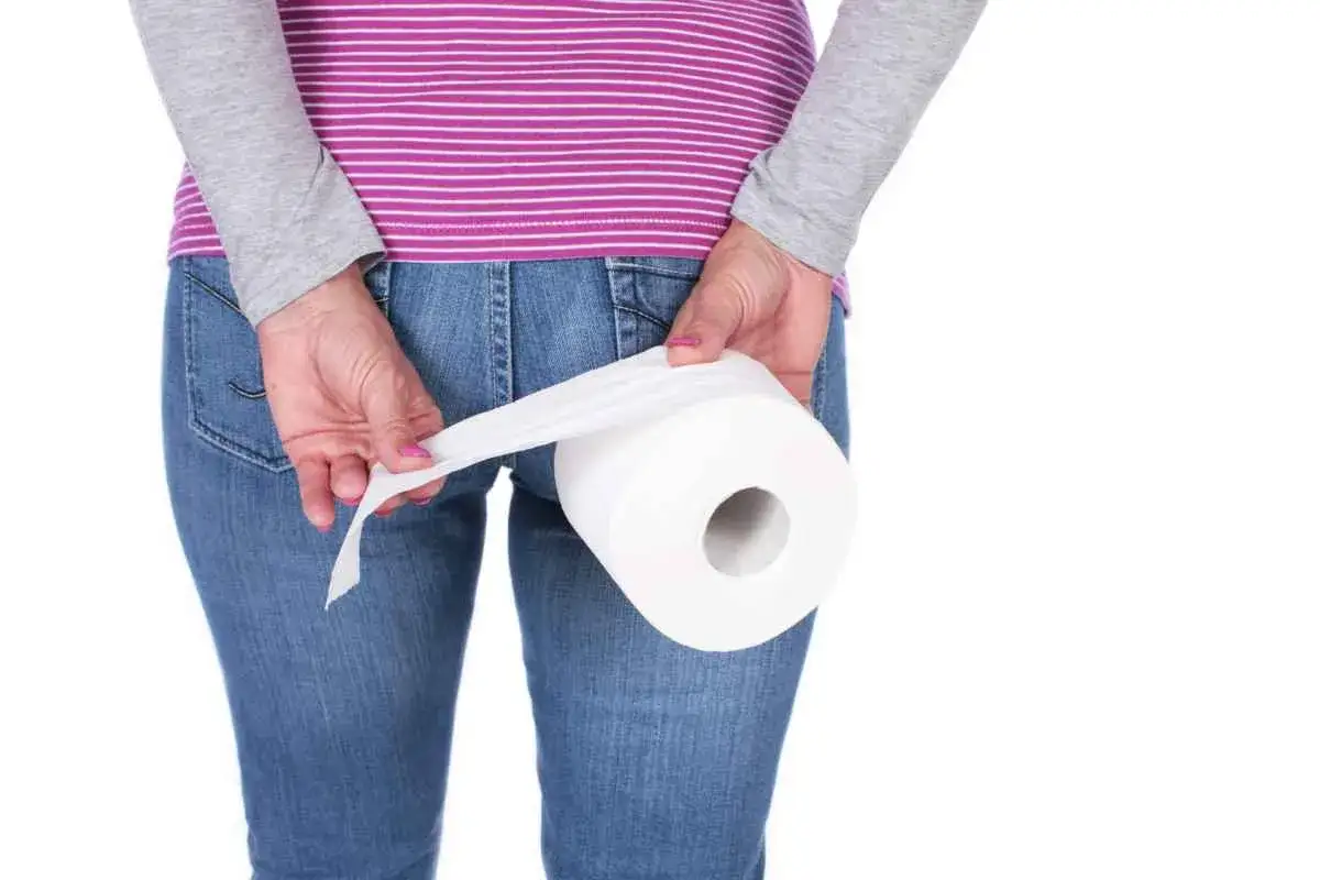Person med jeans och randig tr&ouml;ja h&aring;ller en toalettrulle. Kan vara relaterat till hemorrojder blod.