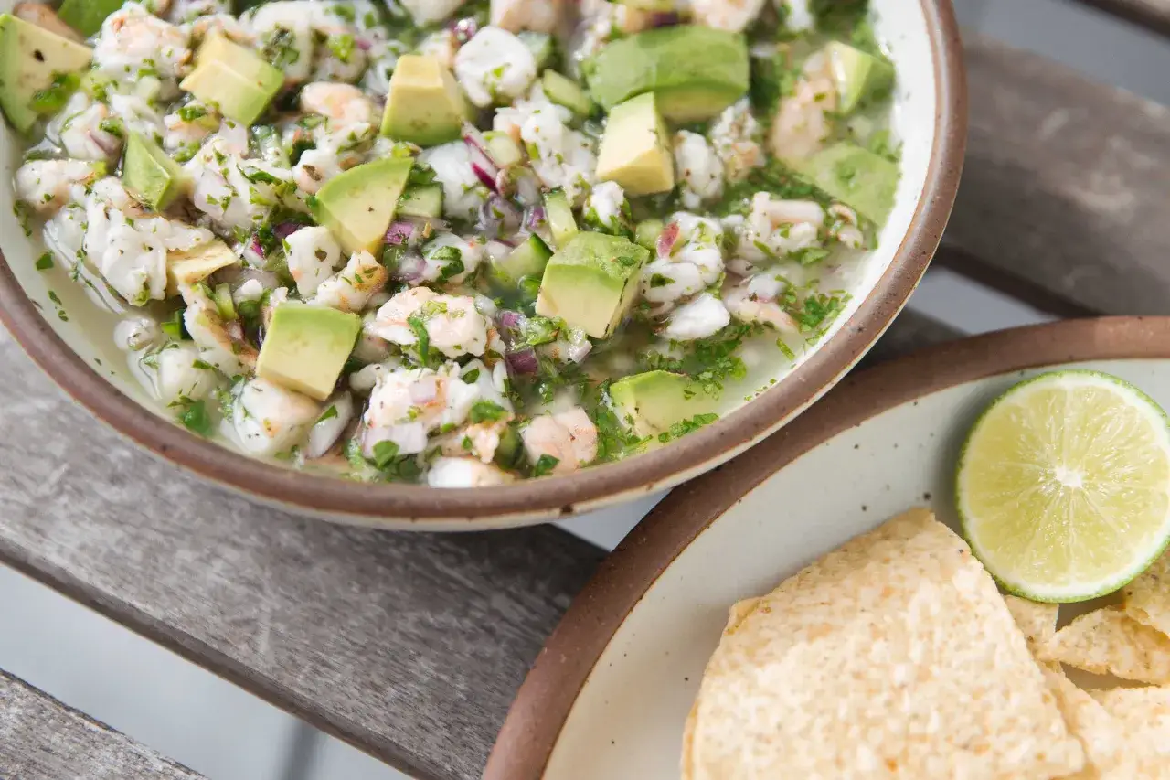 En sk&aring;l med f&auml;rsk ceviche med r&auml;kor, avokado och koriander. Perfekt f&ouml;r ett somrigt ceviche recept. Serveras med tortillachips och lime.