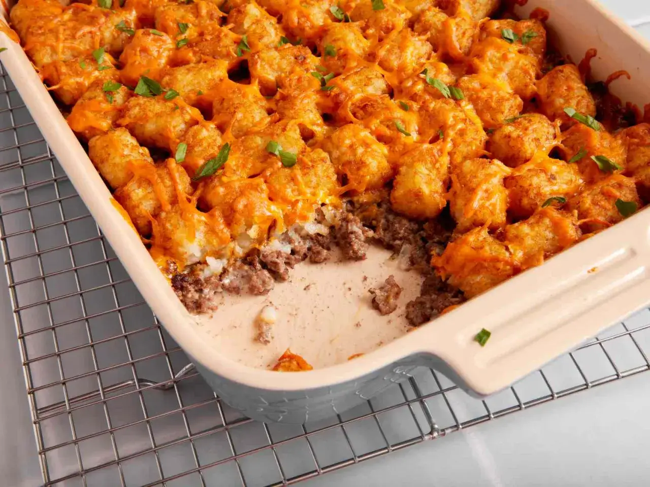 En ugnsform fylld med k&ouml;ttf&auml;rs och toppad med gyllene tater tots och sm&auml;lt ost. Garnerad med f&auml;rsk persilja.