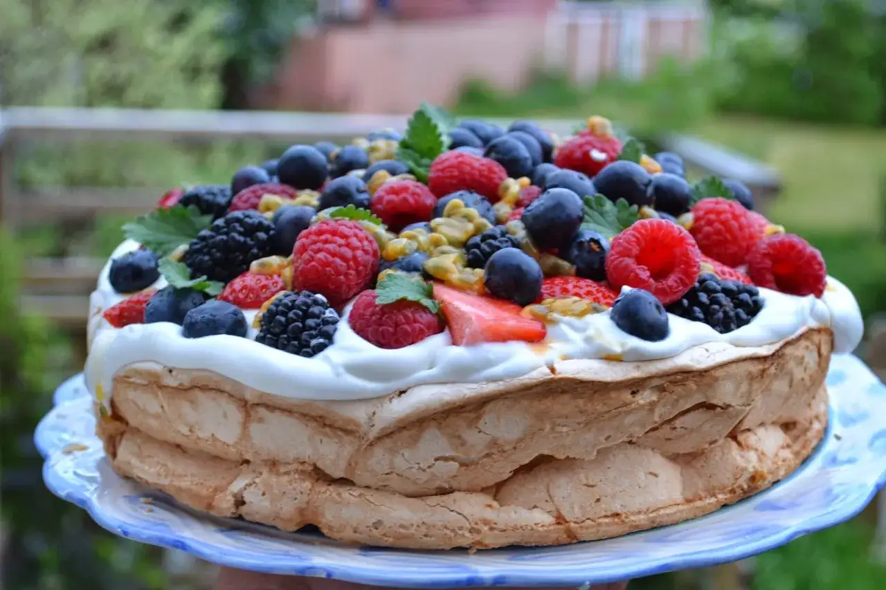 En vacker pavlova med gr&auml;dde och massor av f&auml;rska b&auml;r, perfekt f&ouml;r ett sommarfika. Ett enkelt pavlova recept att prova!