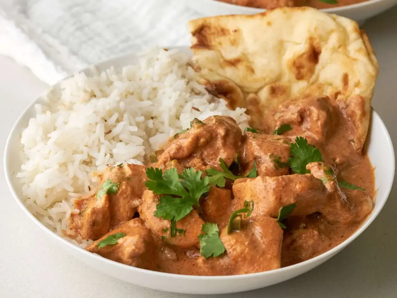 En sk&aring;l med kr&auml;mig kyckling tikka masala, ris och naanbr&ouml;d. Ett perfekt tikka masala recept f&ouml;r en smakrik middag.