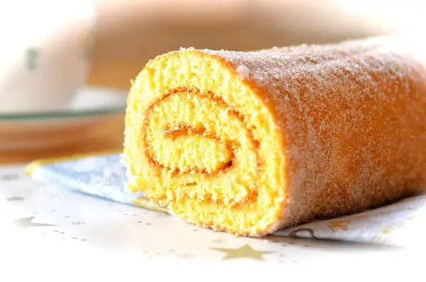 En saftig glutenfri rulltårta med socker strött över, perfekt för fikat.