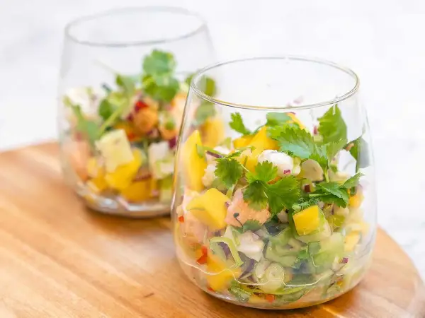 Två glas med färgglad ceviche, perfekt för ett somrigt ceviche recept med mango, koriander och chili.