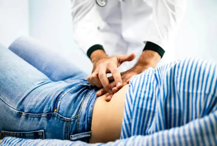 Läkare undersöker en patient som har ont i magen.